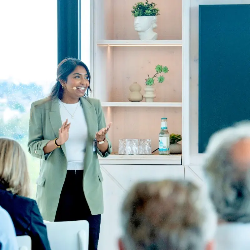 Sharuga Vigneswaran spricht mit Headset vor Publikum.