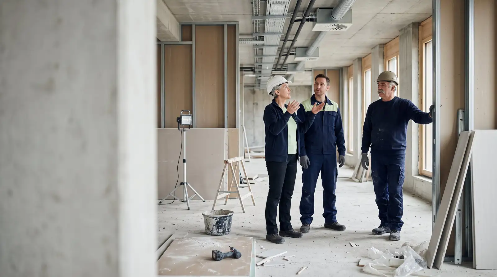 Bauherrenvertreterin, Bauleiter und Polier bleiben beim Rundgang durch den Ausbau stehen und besprechen, was sie sehen.